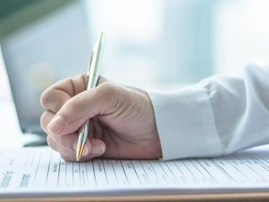 A person is writing on a piece of paper with a pen.