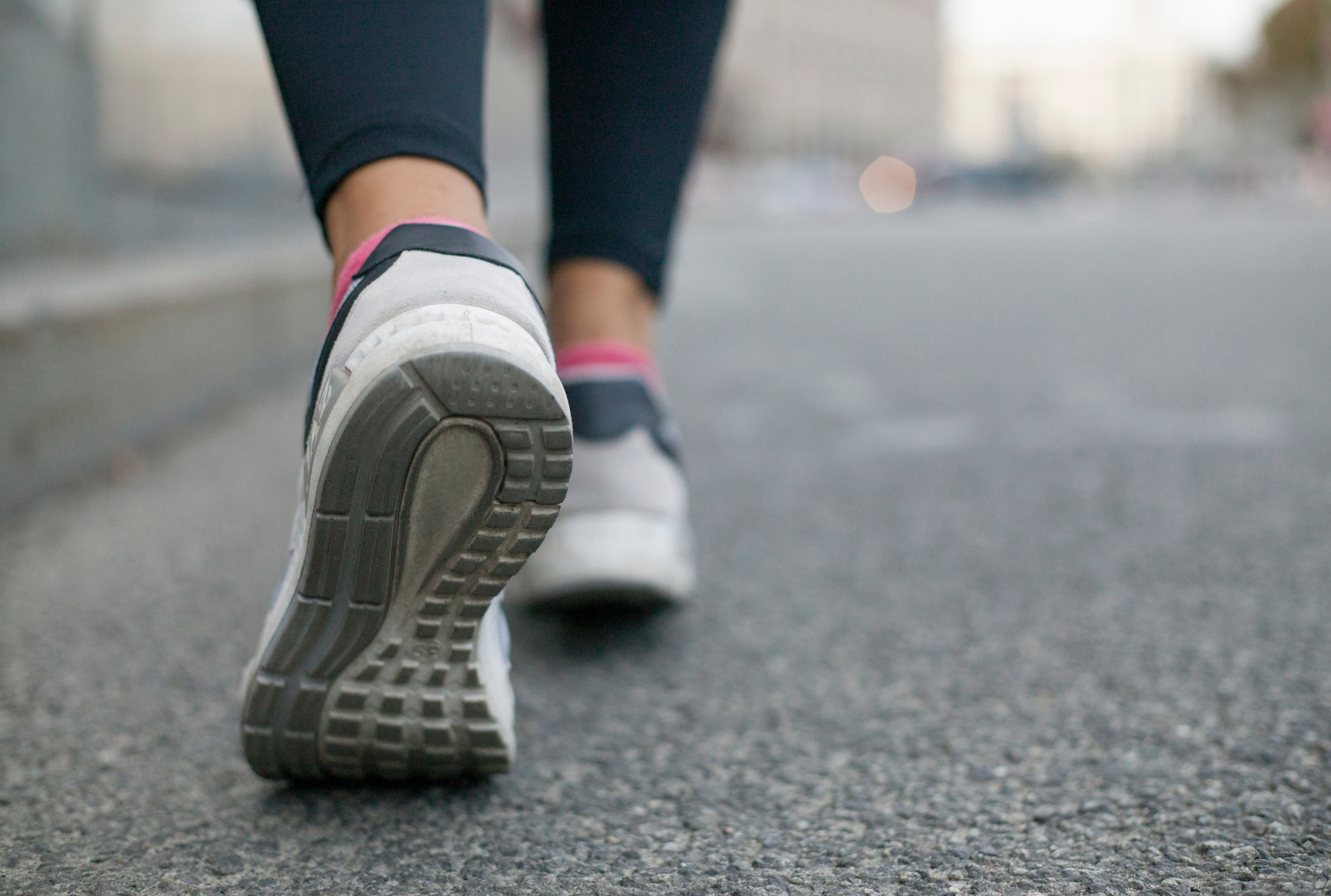 A close up of a person 's feet walking down a street.