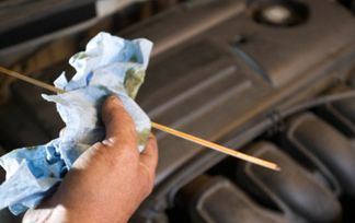 Una persona está comprobando el nivel de aceite de un coche con una varilla de nivel.