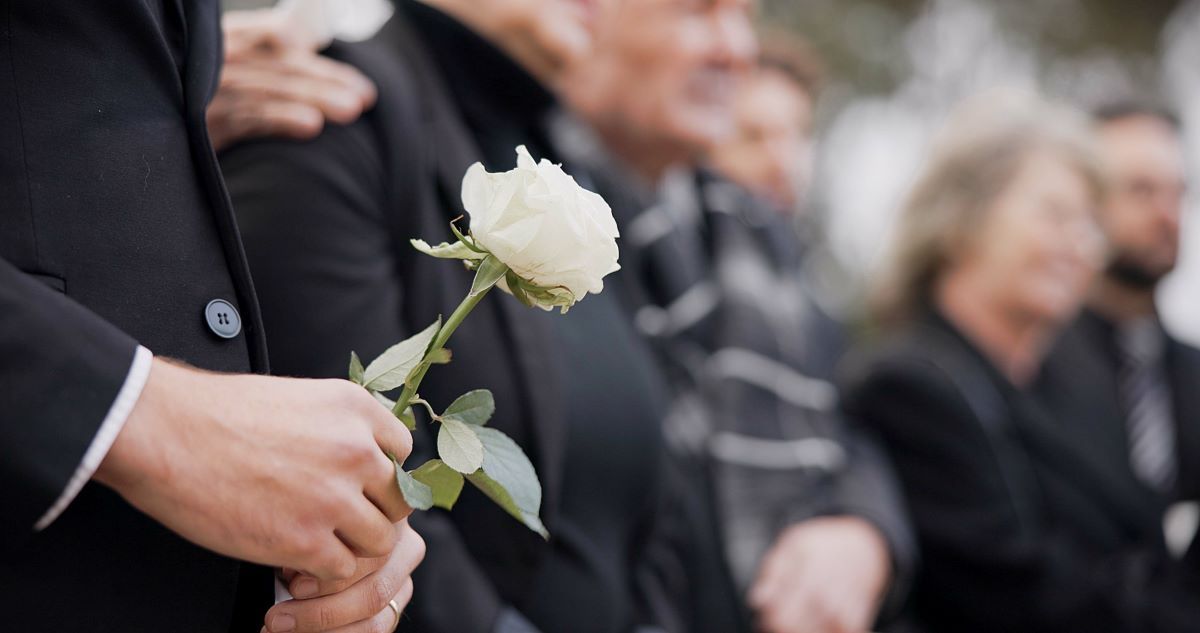 A group of people are standing around a coffin at a funeral.