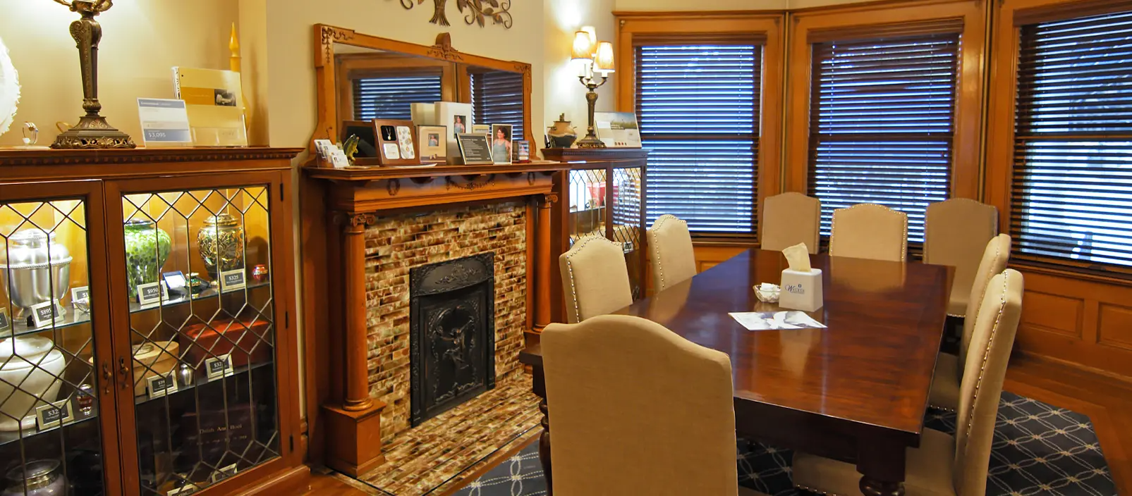 A dining room with a wooden table, chairs, fireplace, and windows.