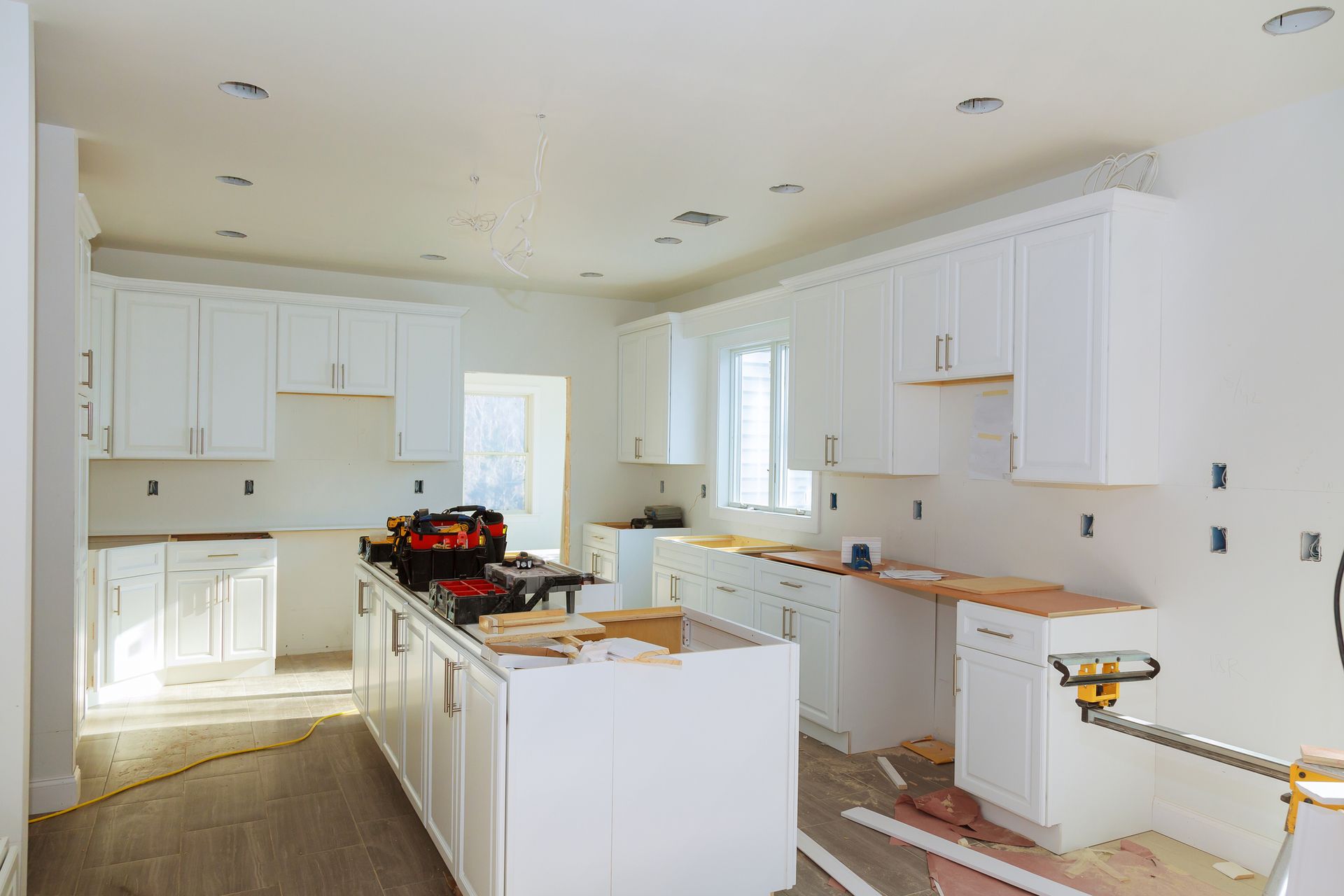 A kitchen under construction with white cabinets and a large island.
