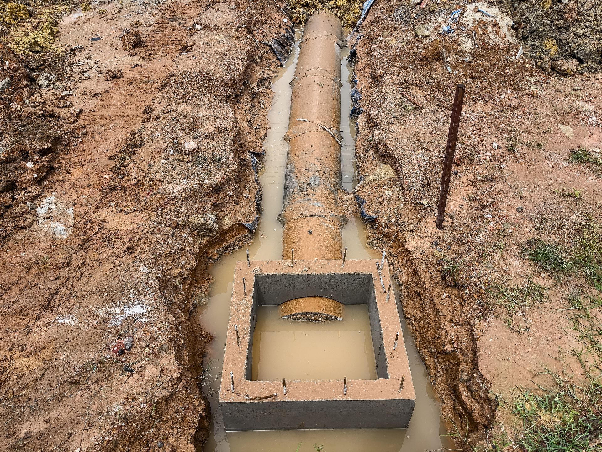 A large pipe is being installed in a muddy area.