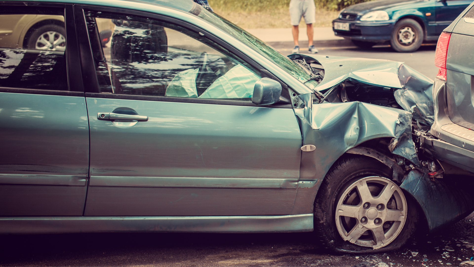 Two cars collided in a street crash, with the front of a silver sedan crushed.