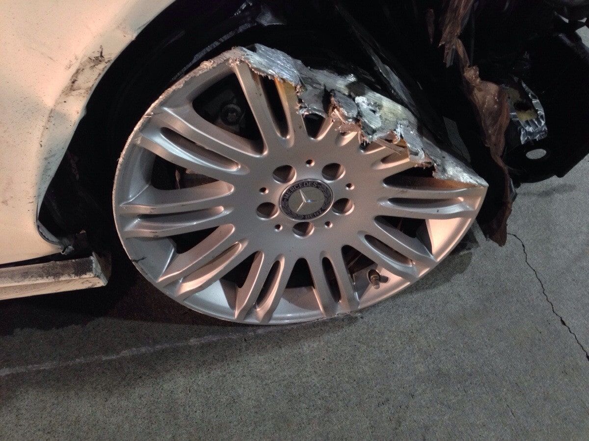 Damaged silver car wheel with a blown tire on a cracked road at night