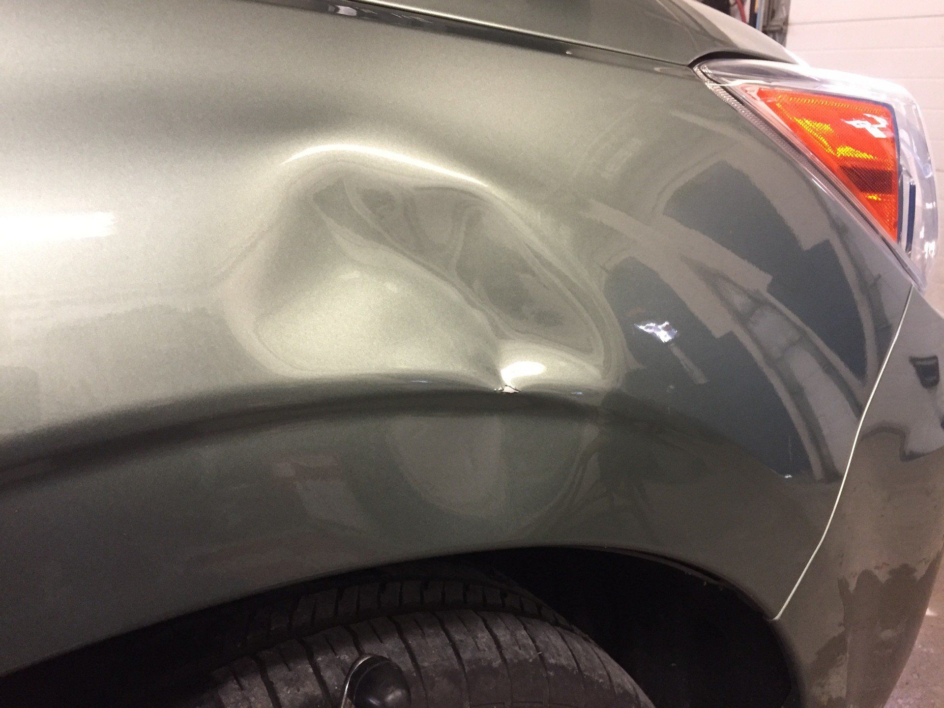 A close up of a car 's fender with a dent in it. - mobile dent removal