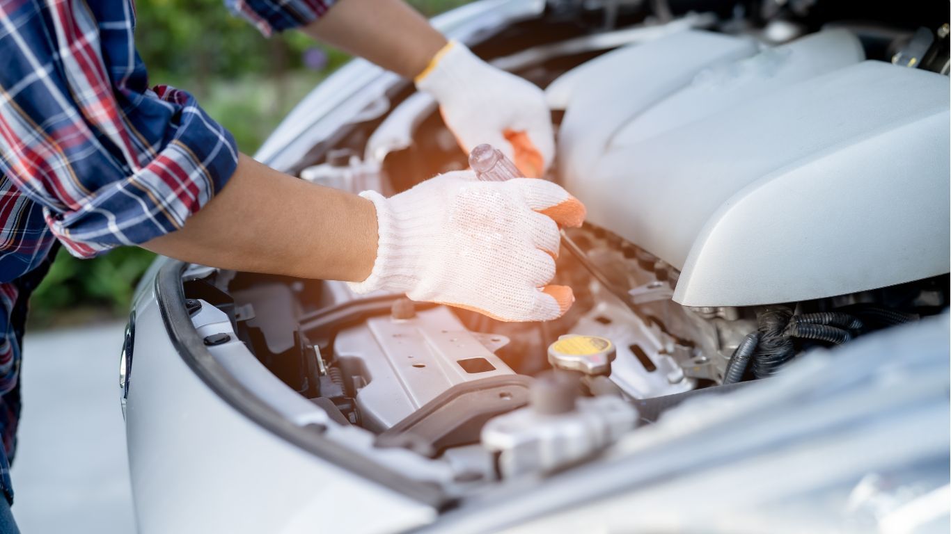 Hands in white gloves inspecting a car engine under an open hood