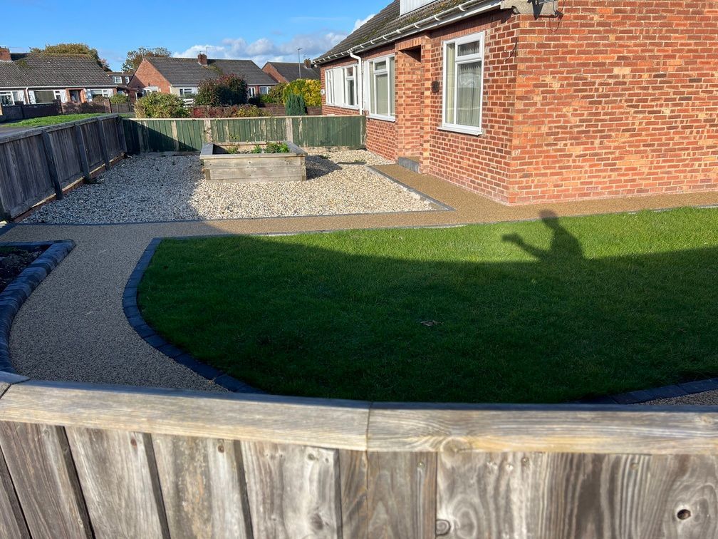 Yellow resin bound pathways with grass and chippings surrounding them.