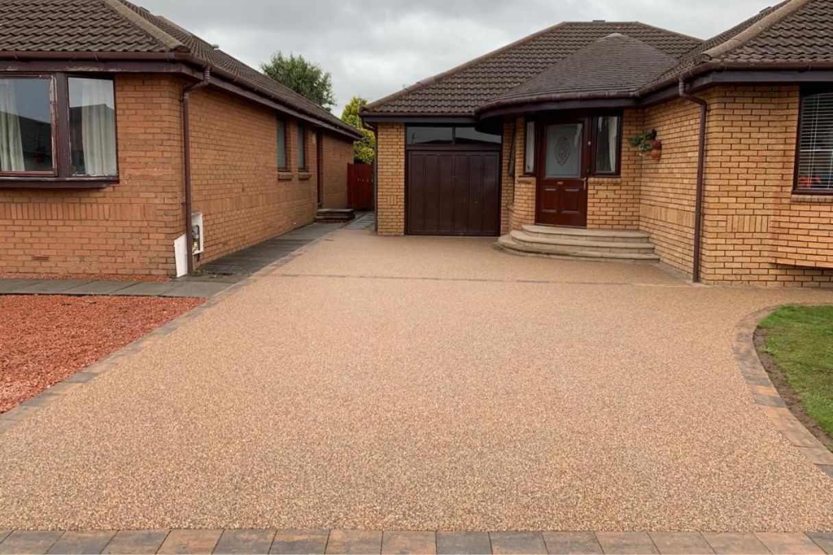 Dark gold resin driveway for a yellow-brick bungalow.