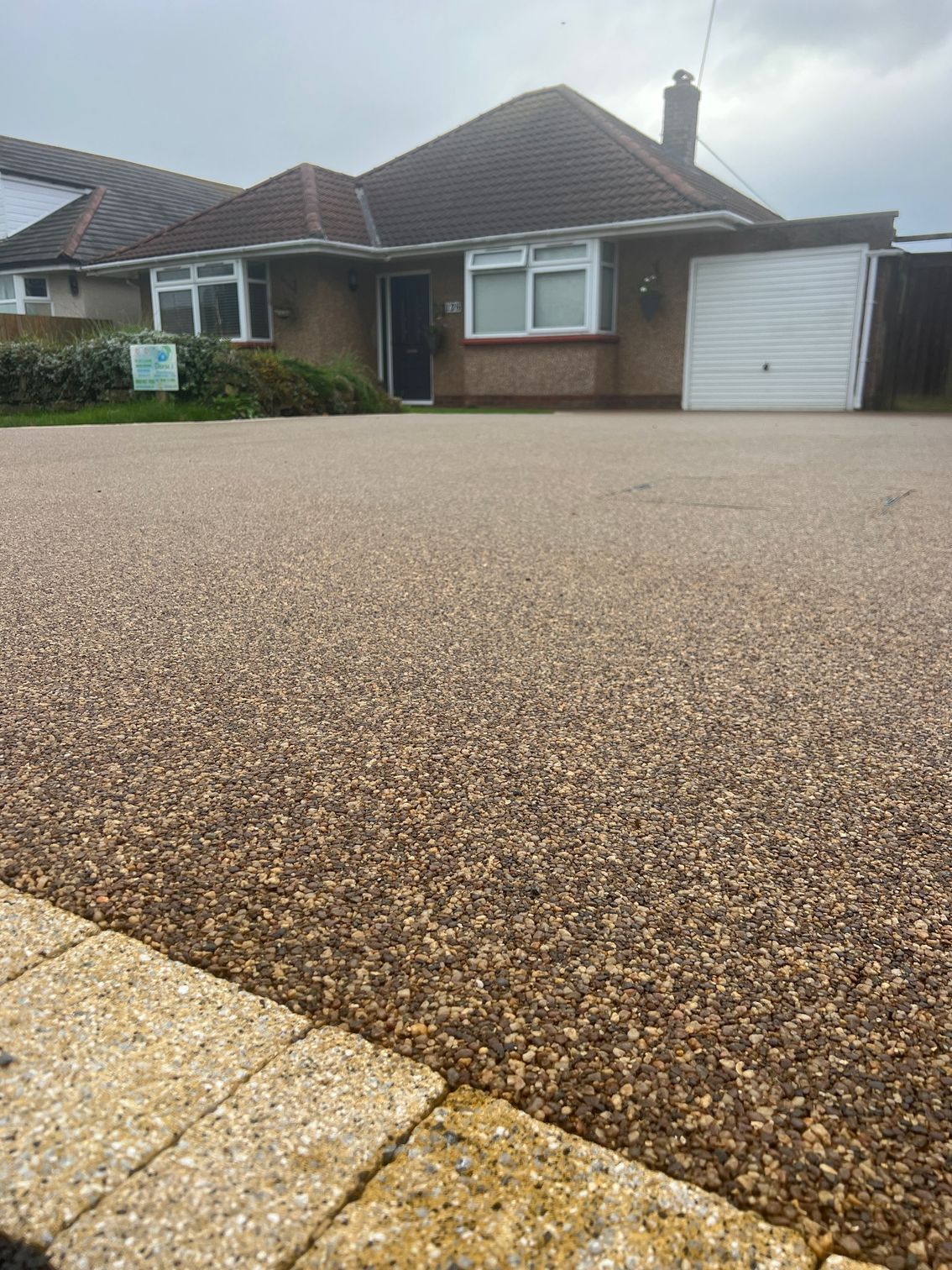 A gravel driveway leading to a house with a brick curb.