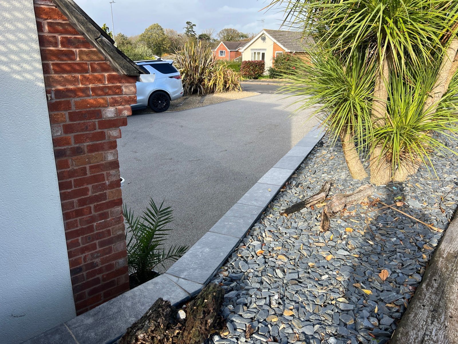 A gravel driveway leading to a house with a brick curb.