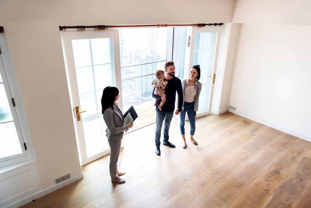 Real Estate Agent Showing a Couple With a Baby a Bright and Empty Room — Country Coast Valuers in Forster, NSW