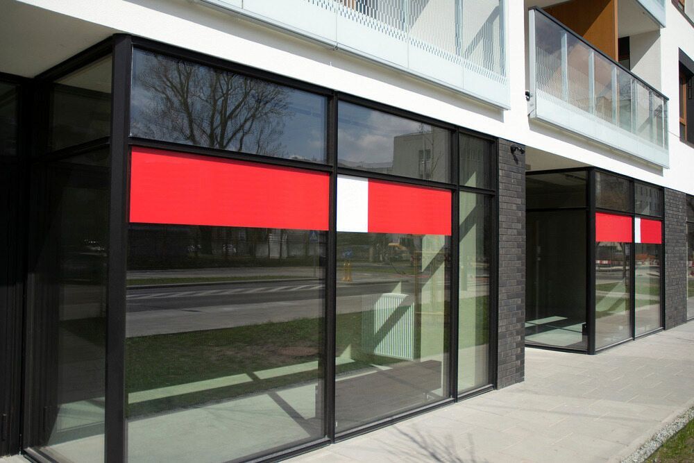 Modern Building Storefronts With Red and White Banners Across Windows — Country Coast Valuers in Forster, NSW