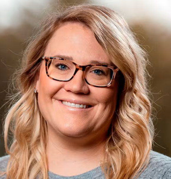 A woman in a blue shirt is smiling for the camera.