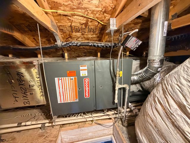 Attic HVAC unit with ductwork and exposed wooden rafters, including insulated air ducts and wiring.