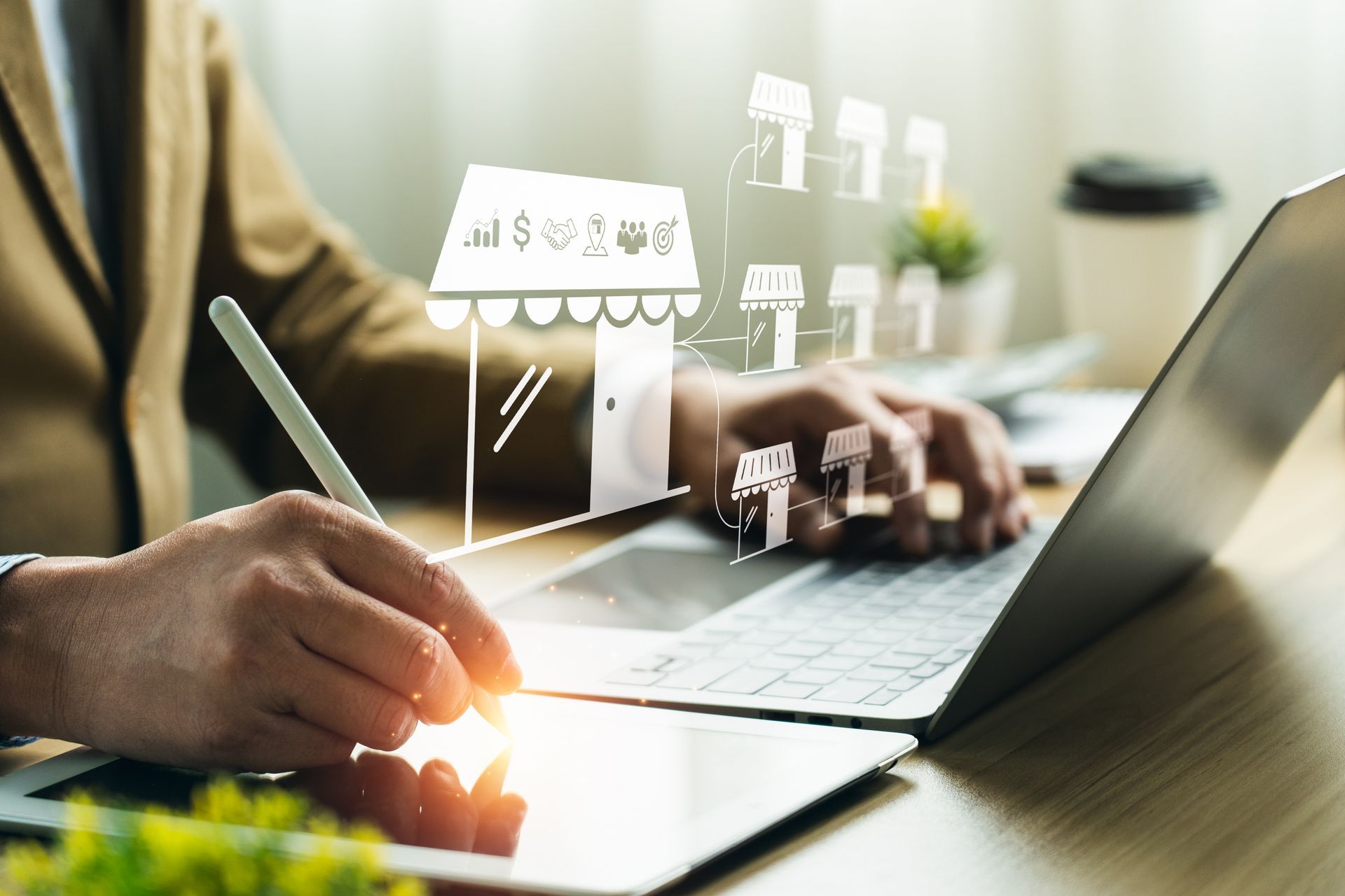 Hands typing on a laptop beside a notebook and pen, with digital business icons floating above the desk.