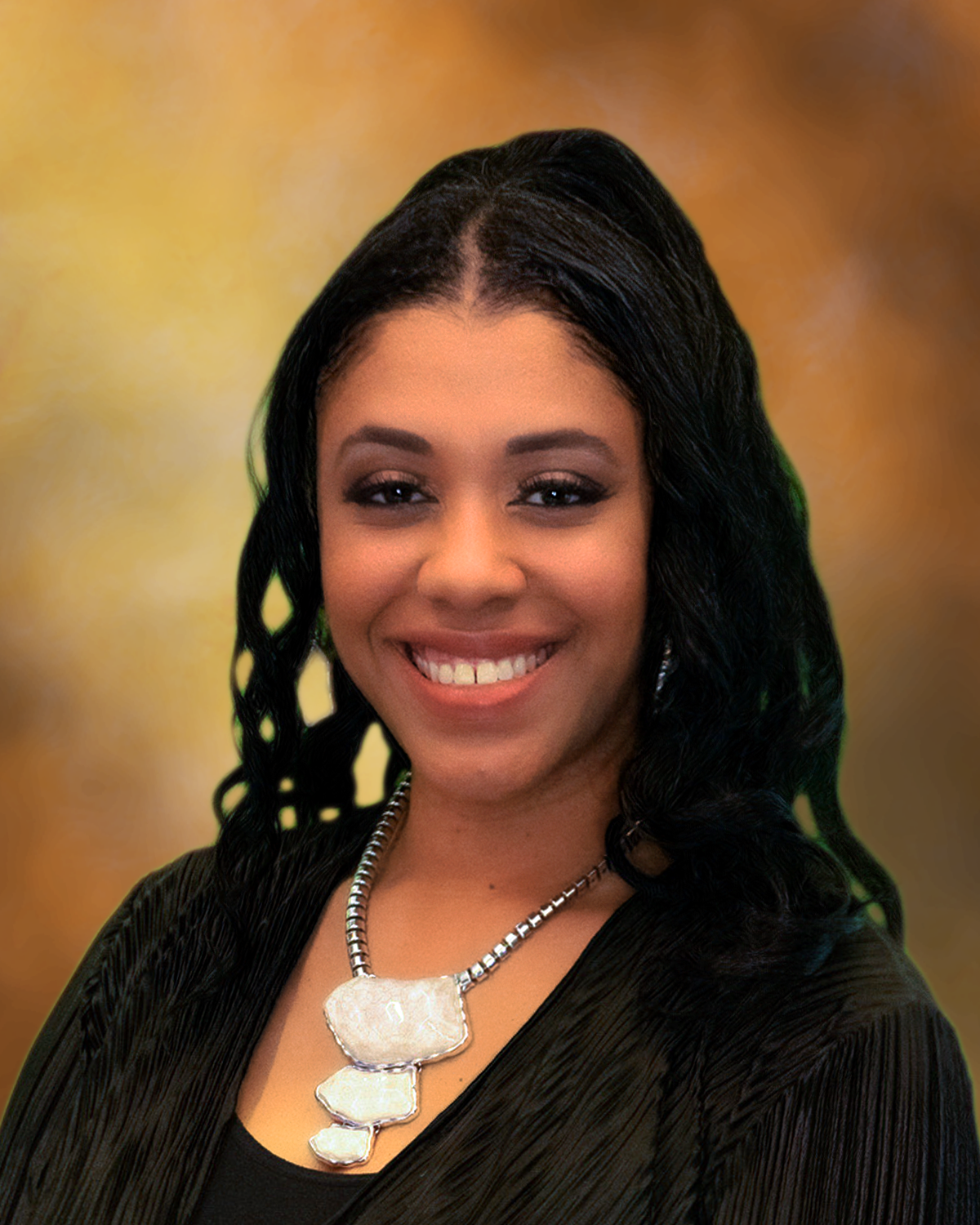 Smiling woman in a black top and silver necklace against a warm brown background