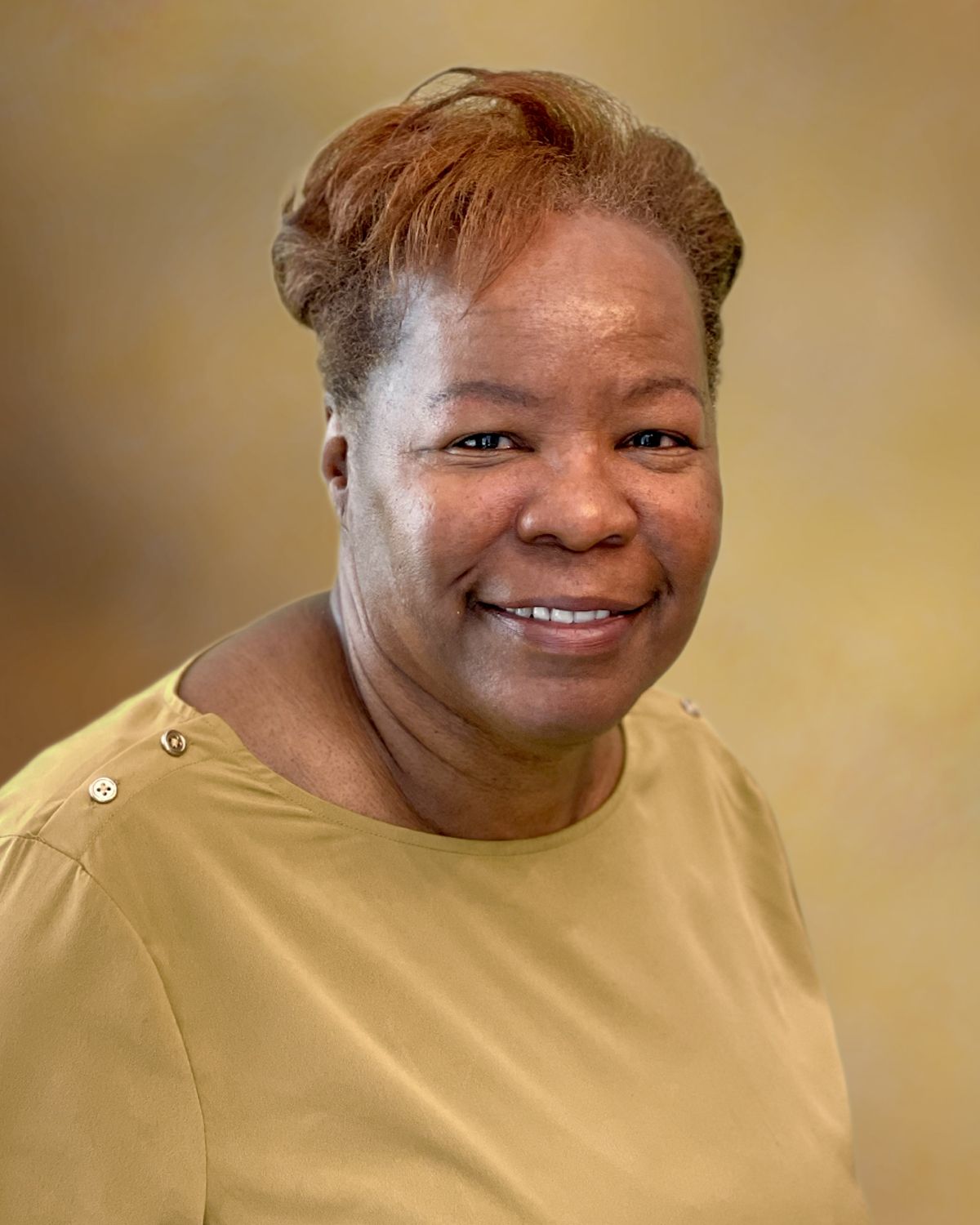 Smiling person in a tan top against a soft beige background