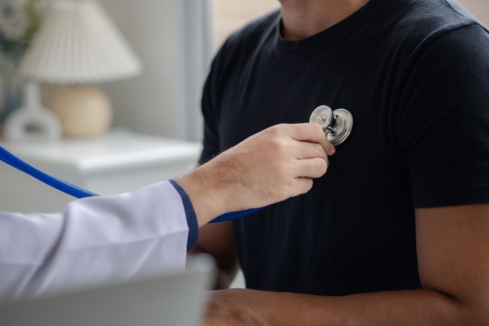 Doctor using a stethoscope to examine a patient's chest in a clinic