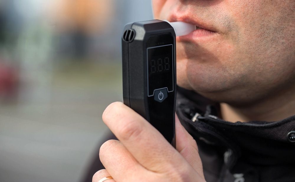 Person speaking into a black handheld device outdoors, with a blurred background