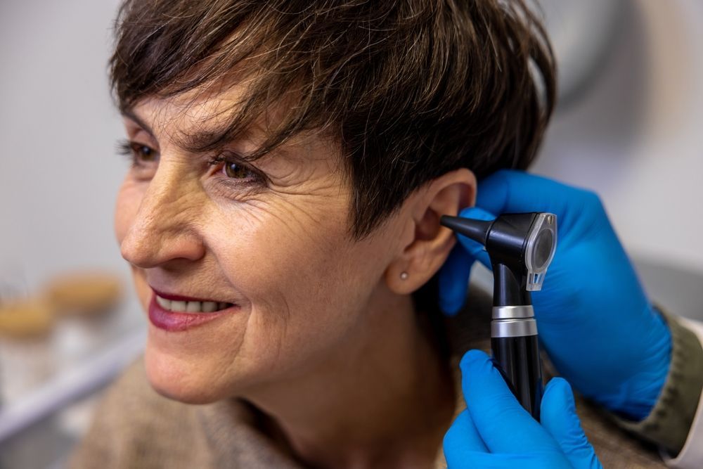 Person having ear examined with an otoscope by a gloved clinician