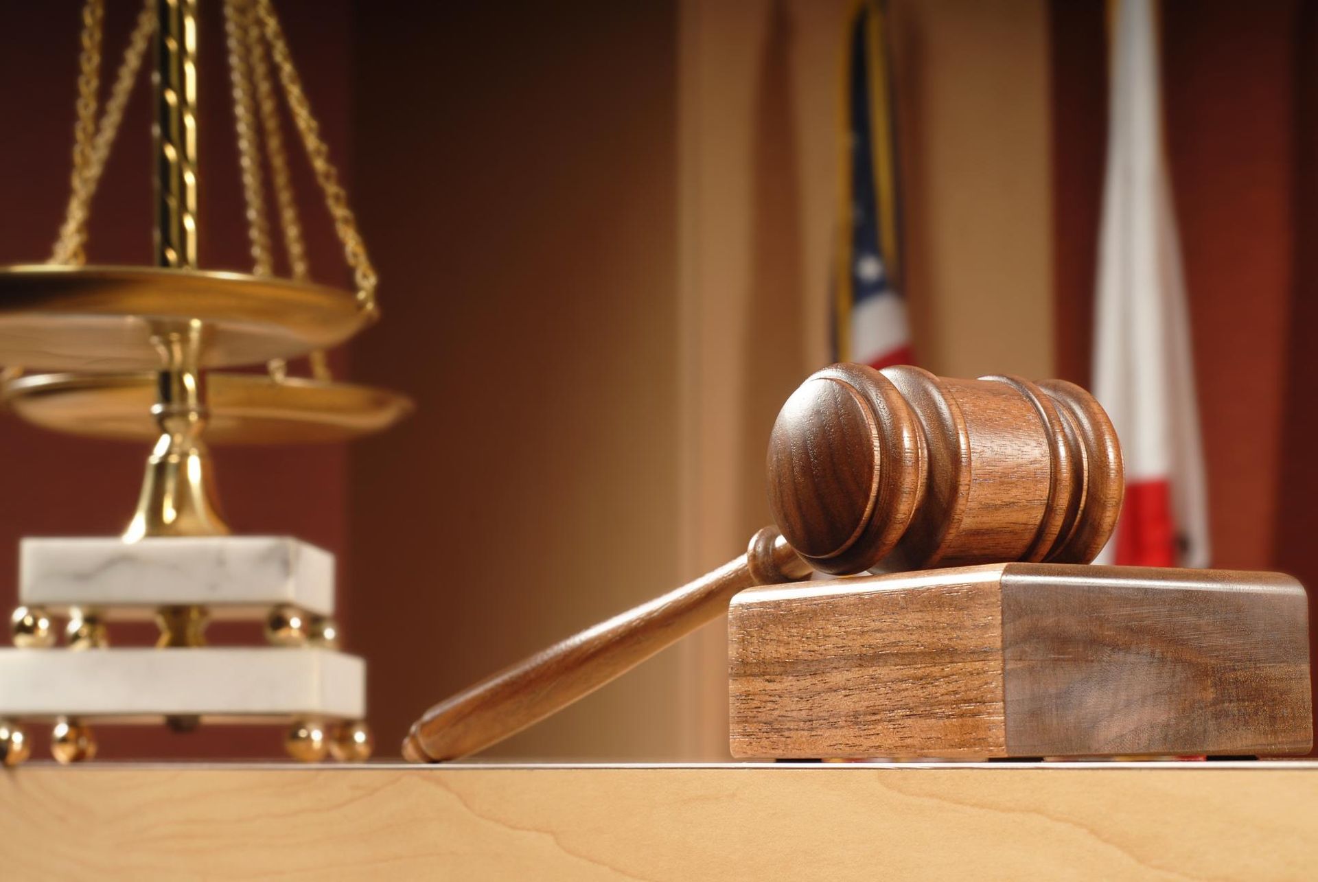 Judge’s gavel on a wooden block beside scales of justice in a courtroom