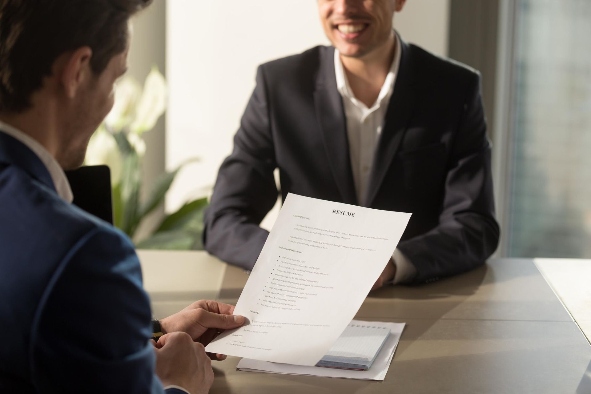Two people in a business meeting, reviewing a document across a table.