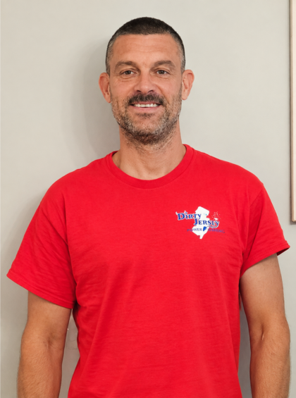 Smiling man in a red T-shirt standing against a plain wall