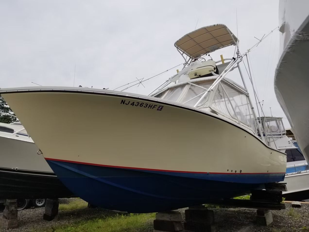 Large white and blue fishing boat on land under an overcast sky