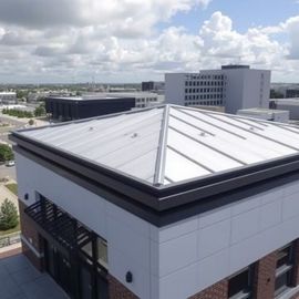 Rooftop view of a modern white building with skylight panels and city buildings in the background
