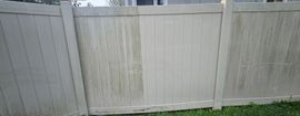 White wooden backyard fence with a gate and grass at the bottom.