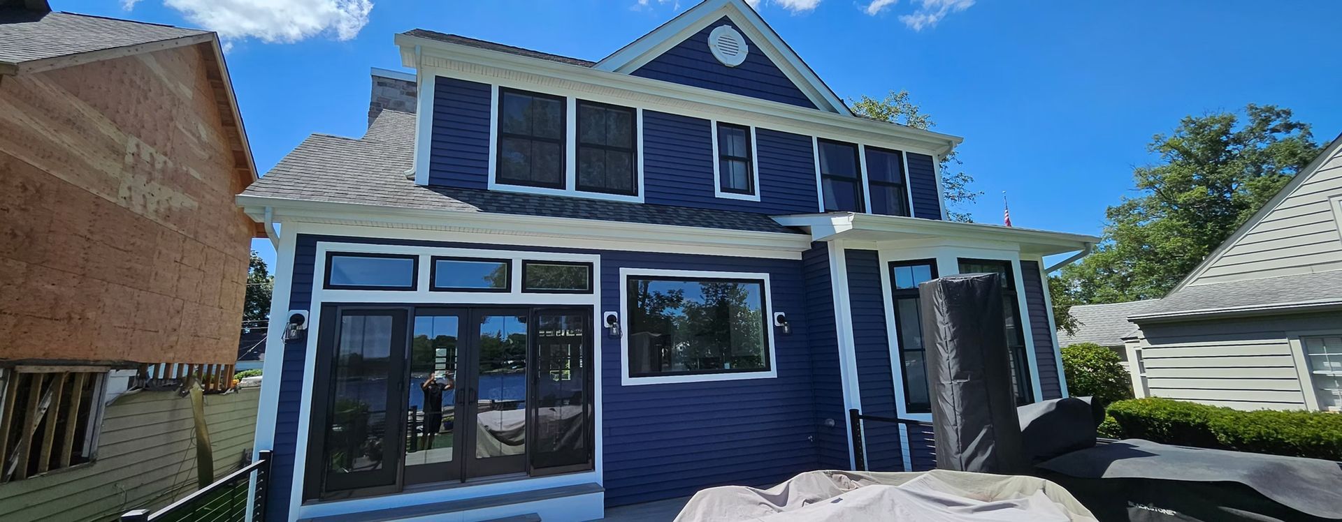 Blue two-story house with white trim and a covered porch on a sunny day