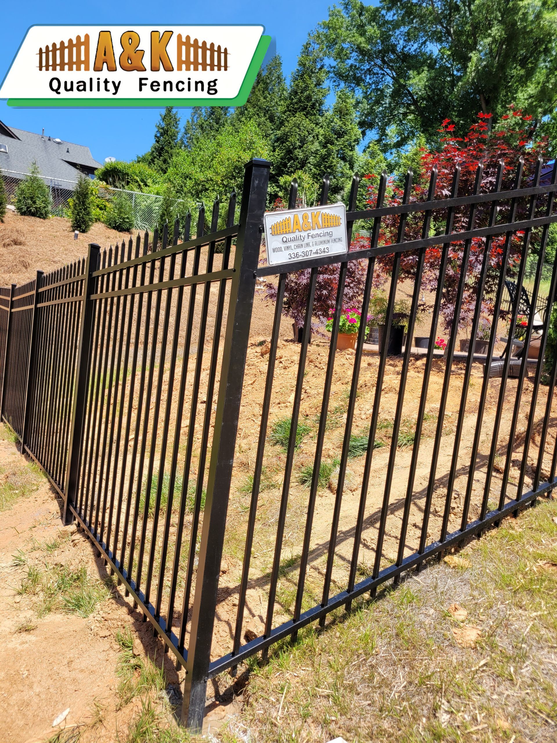 Black metal fence in a yard, with a sign for 