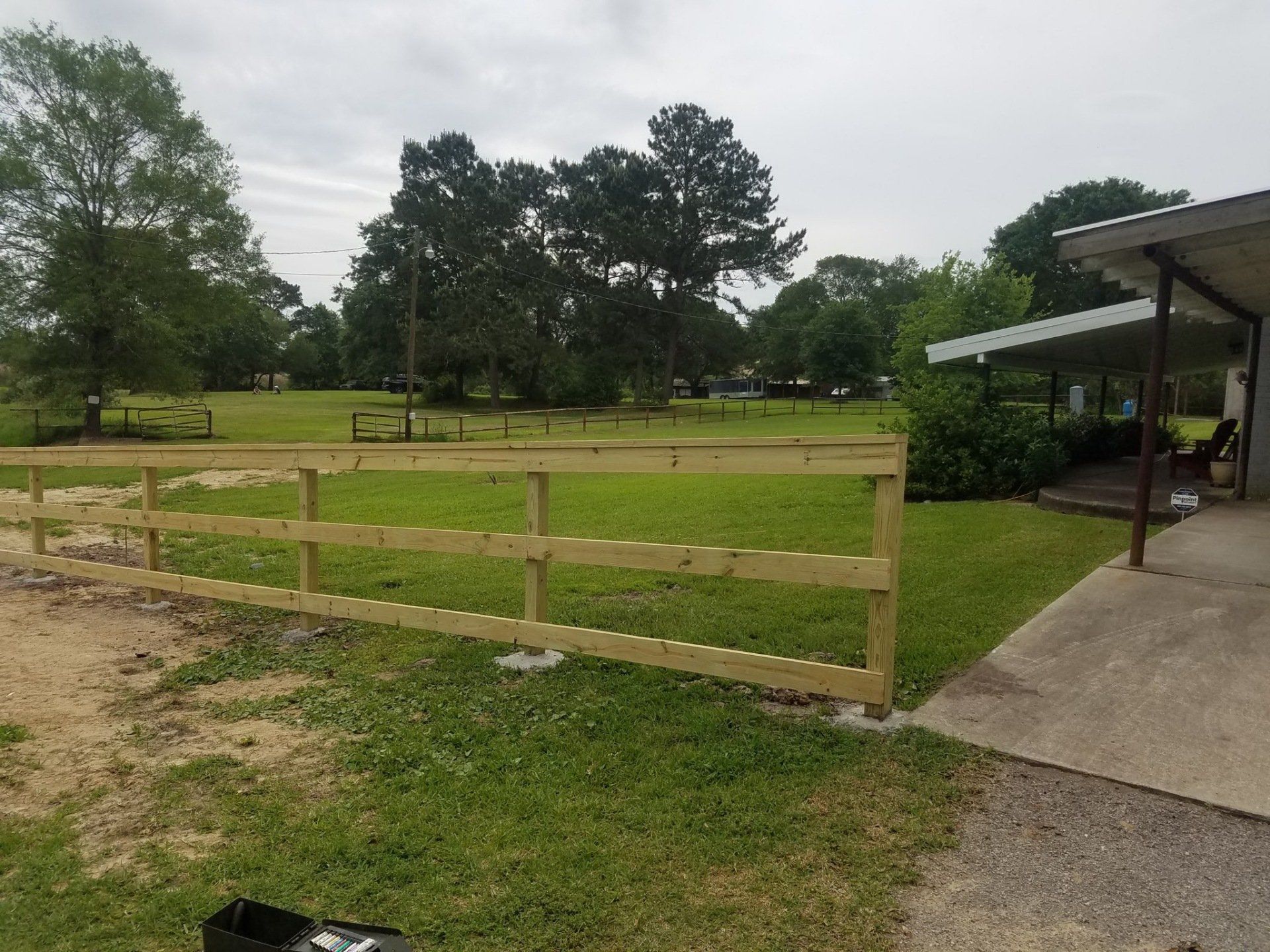 New wooden fence bordering a grassy yard next to a concrete porch.