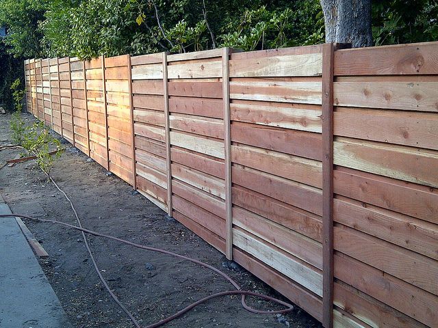Wooden fence in a yard, made of horizontal planks, brown color.