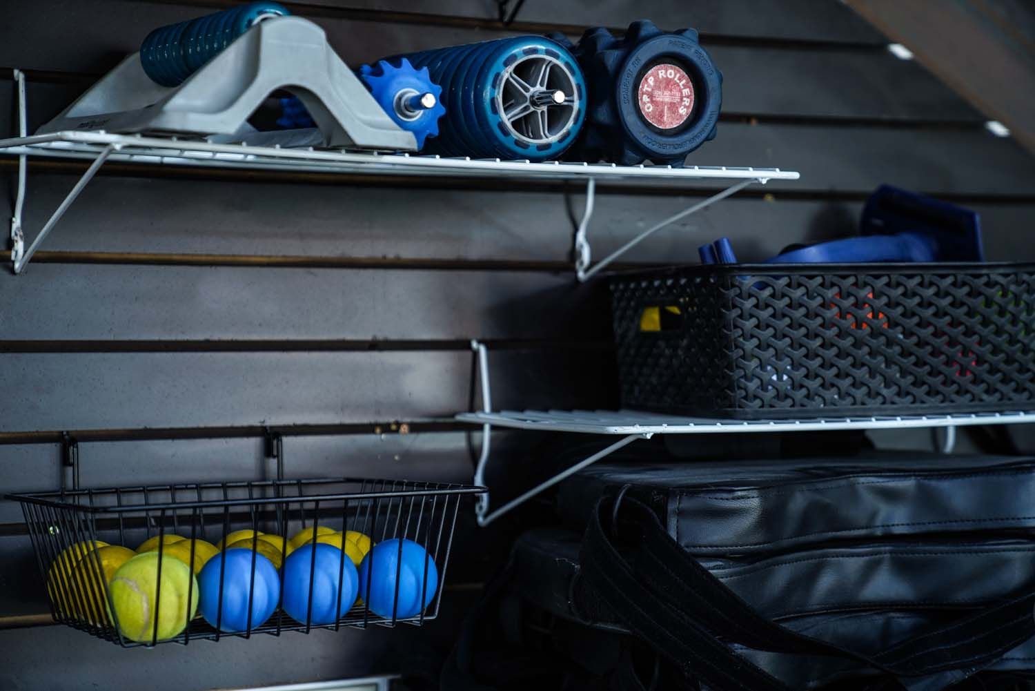 A shelf with a basket of tennis balls and a bag on it.