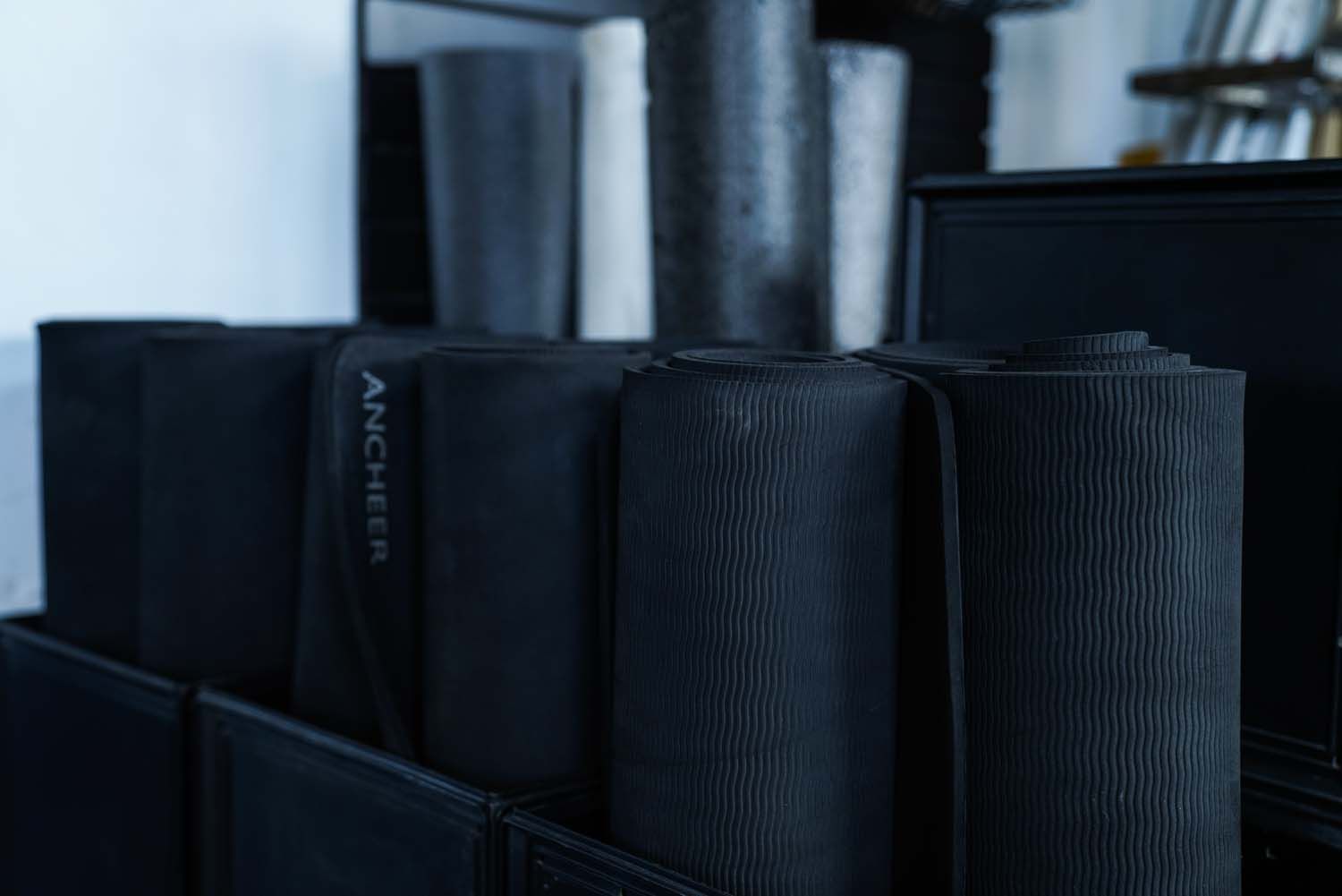 A row of black yoga mats sitting on top of each other on a shelf.