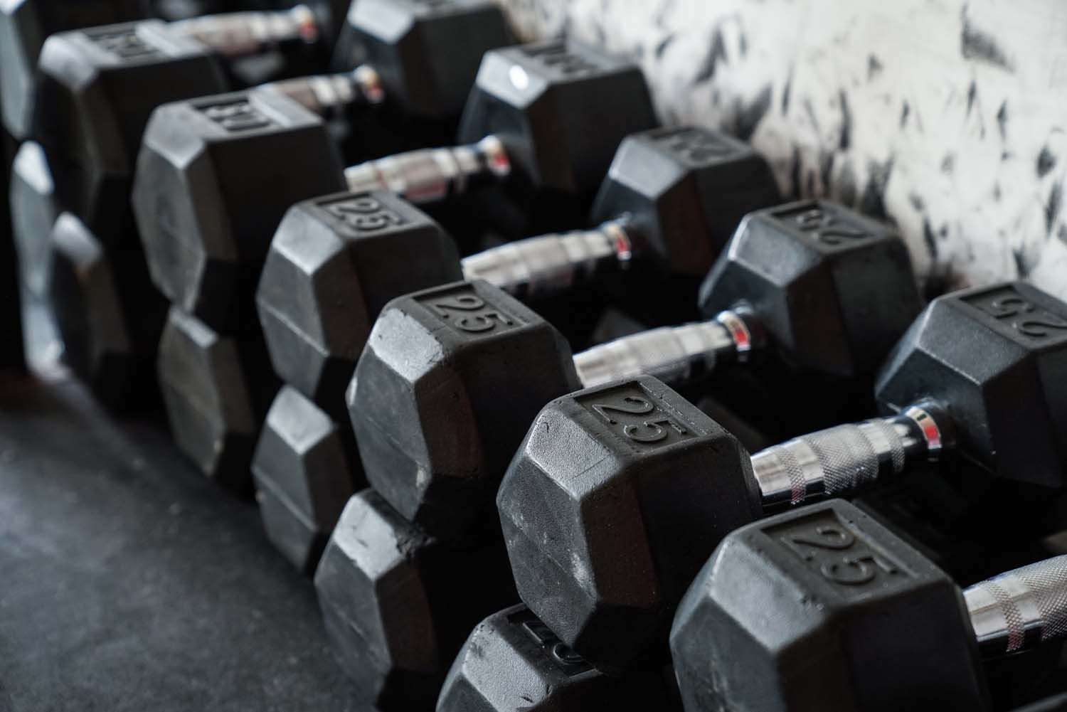 A row of black dumbbells stacked on top of each other in a gym.