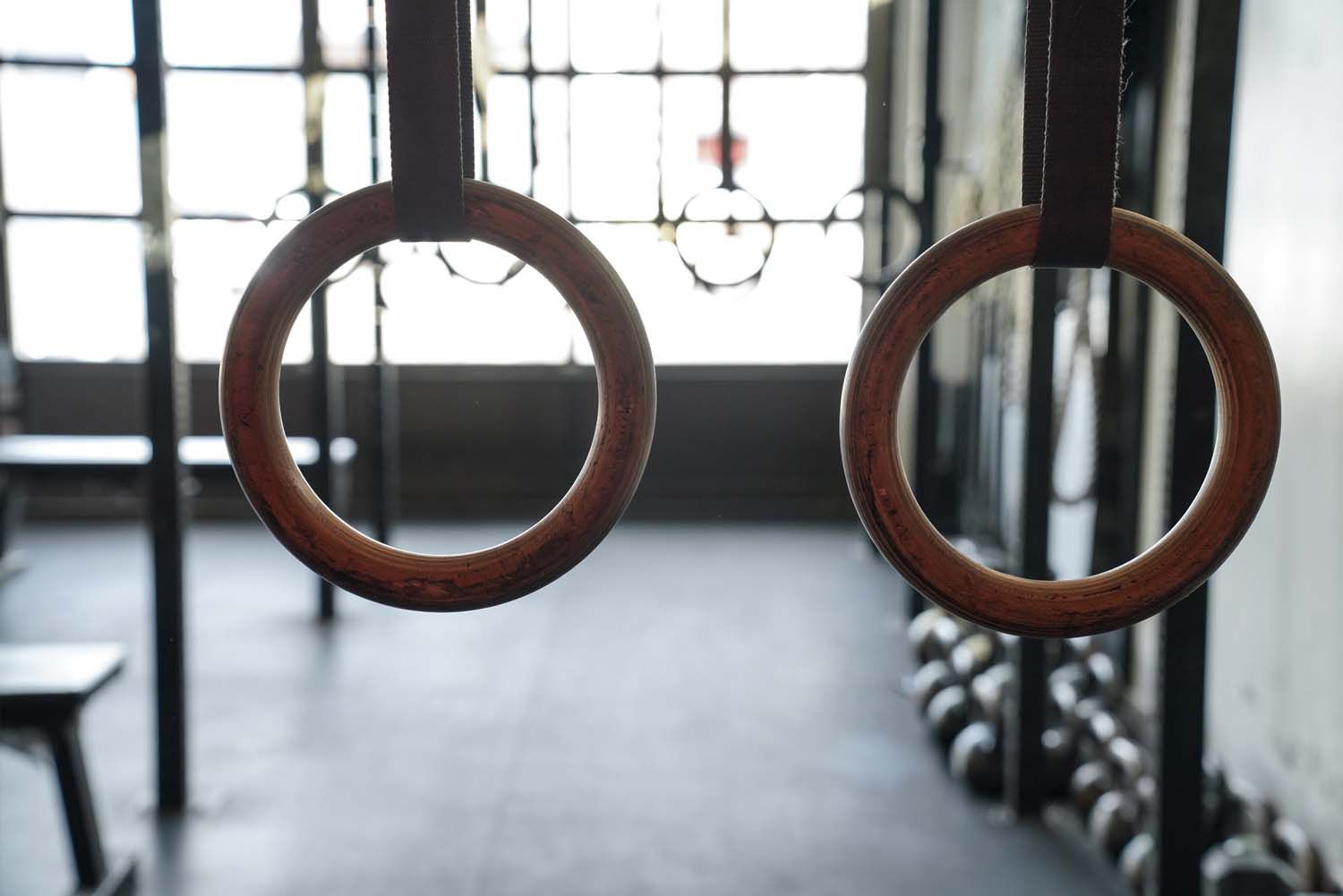 A pair of wooden gymnastic rings hanging in a gym