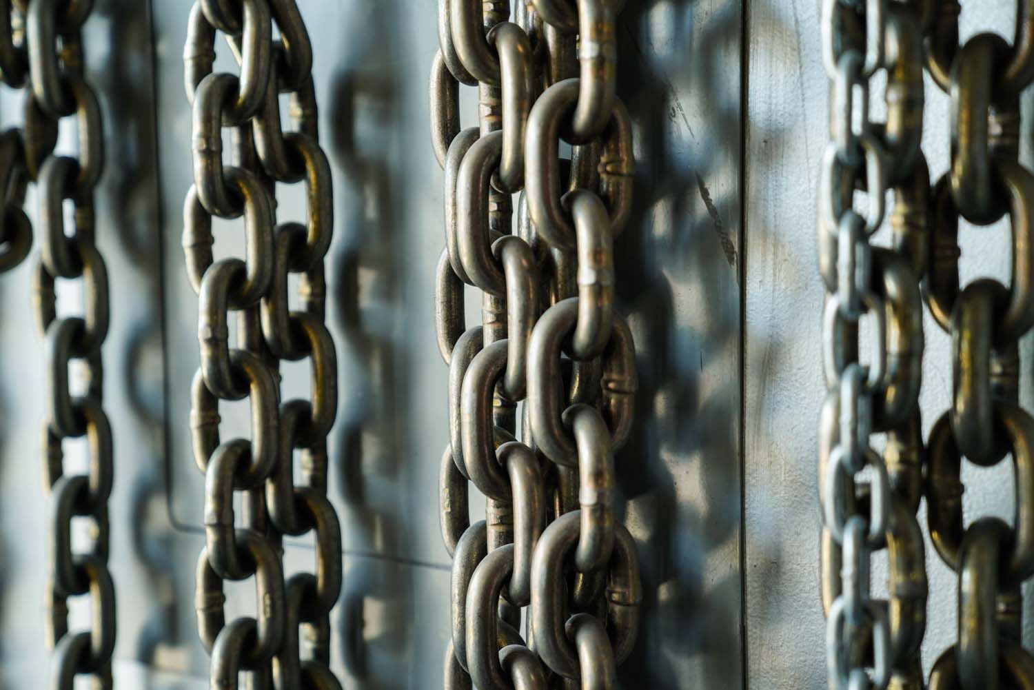 A close up of a bunch of chains hanging from a wall.