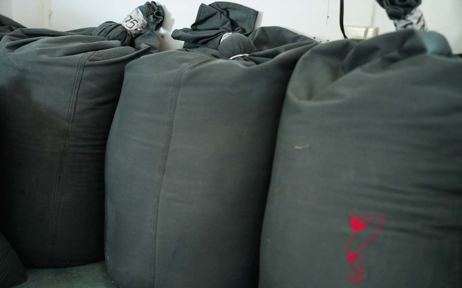 A bunch of black bags are stacked on top of each other in a room.