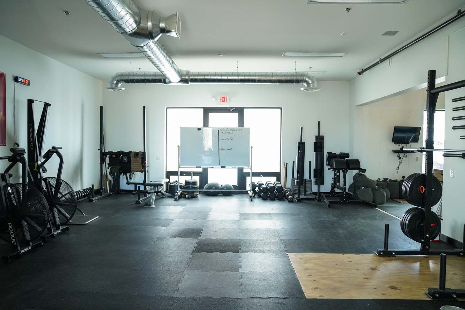 An empty gym with a lot of equipment and a large window.