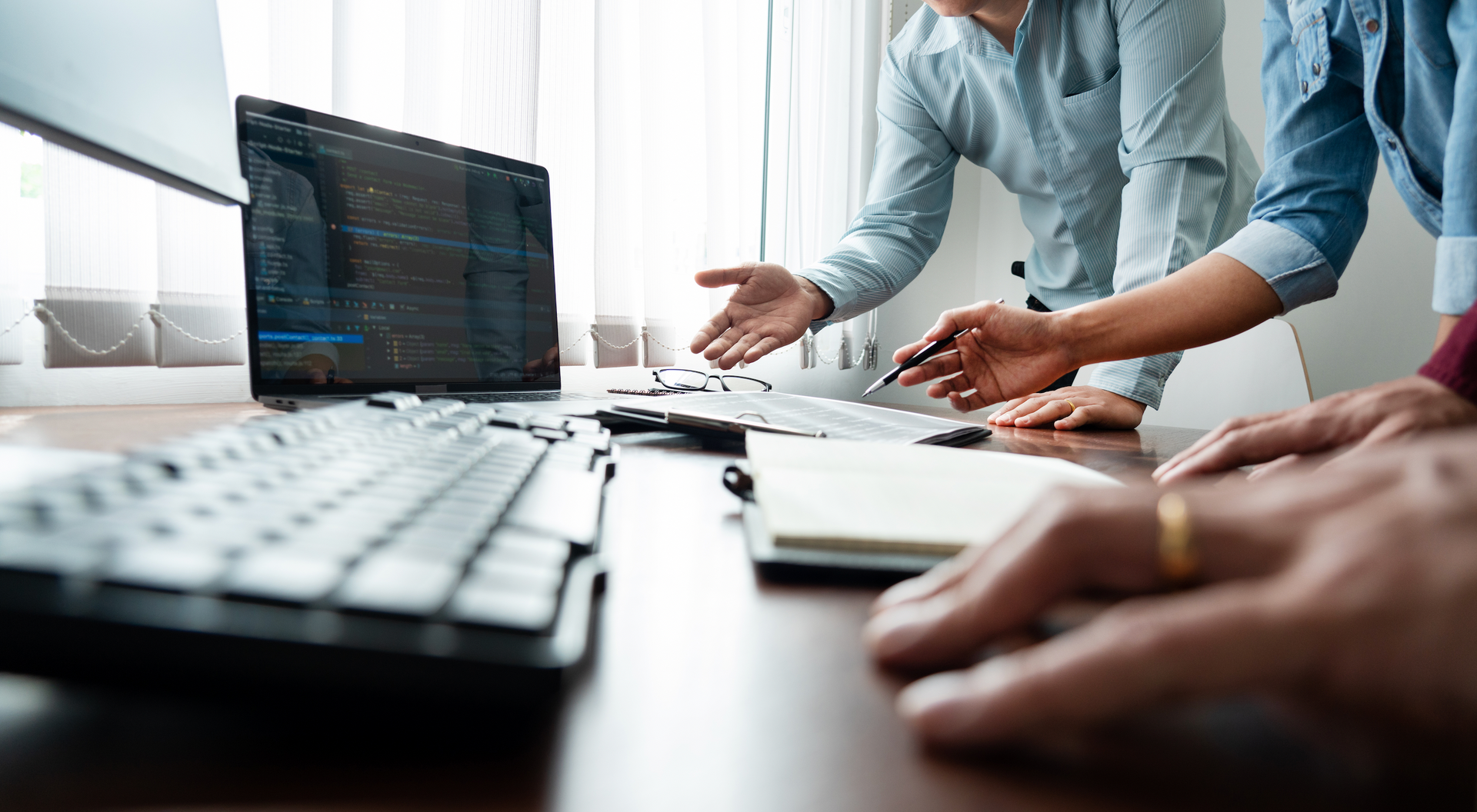 A group of people are sitting at a table looking at a laptop computer.