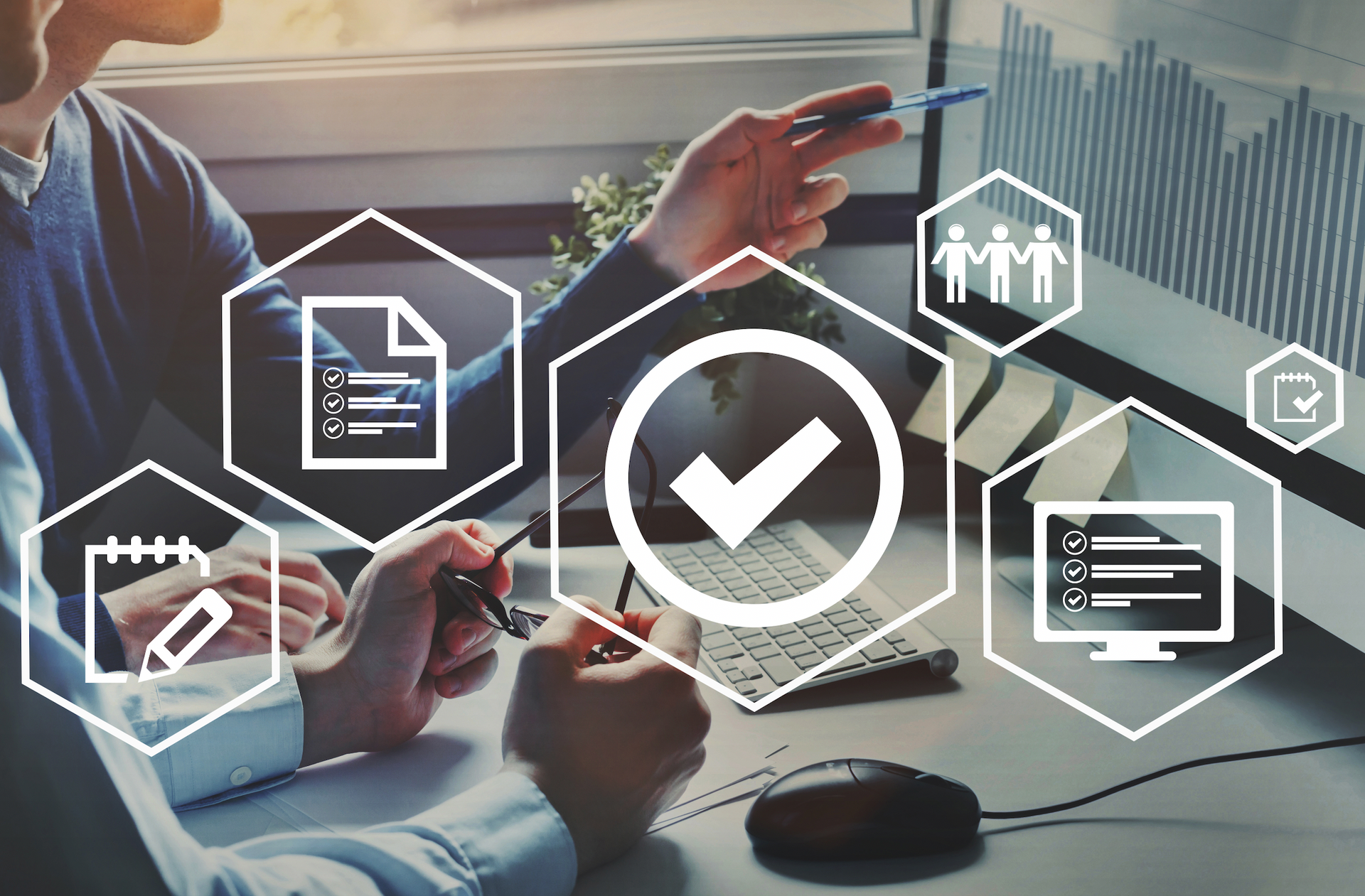 Two men are sitting at a desk looking at a computer screen.