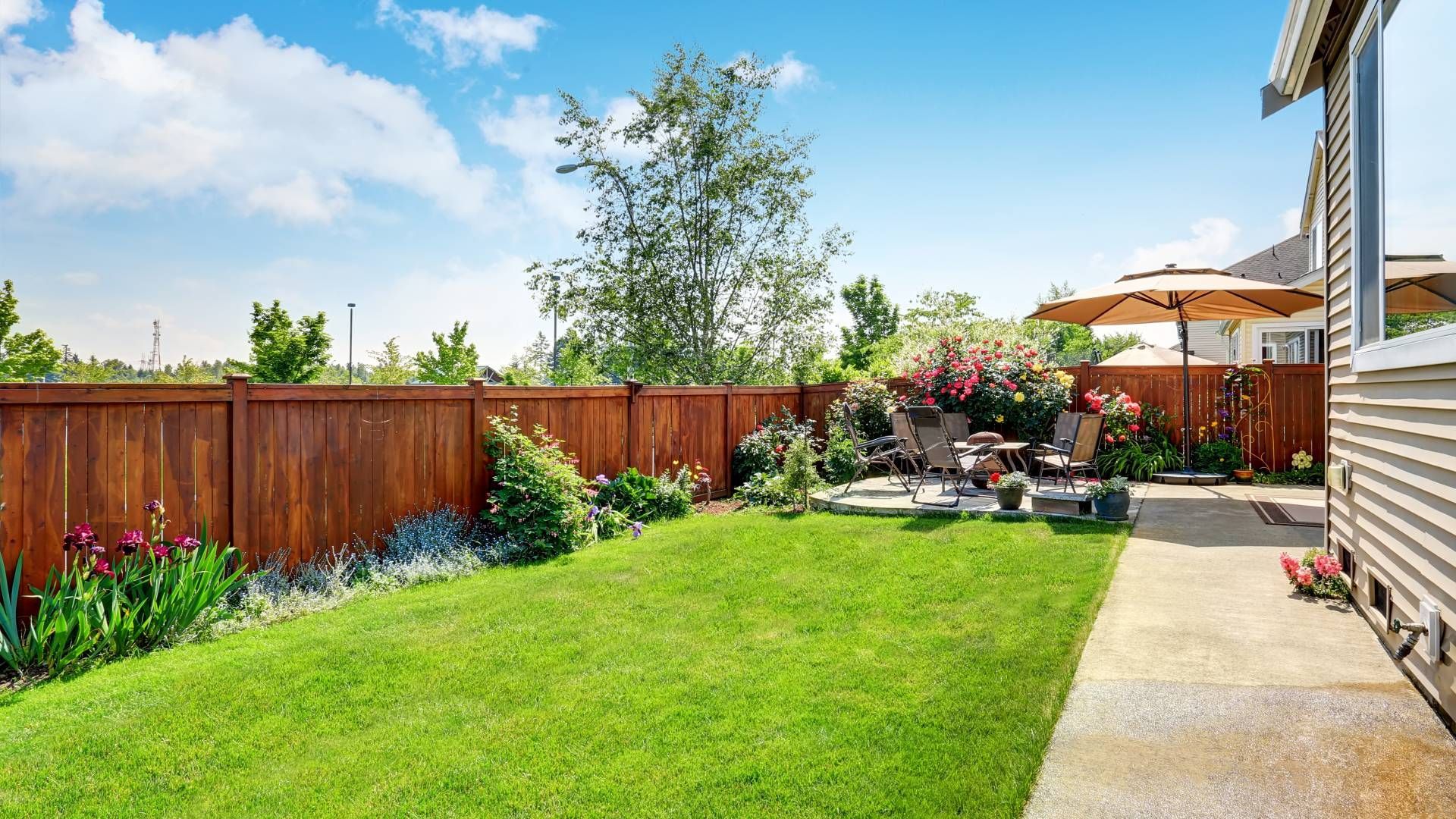 A backyard with a wooden fence and a patio.