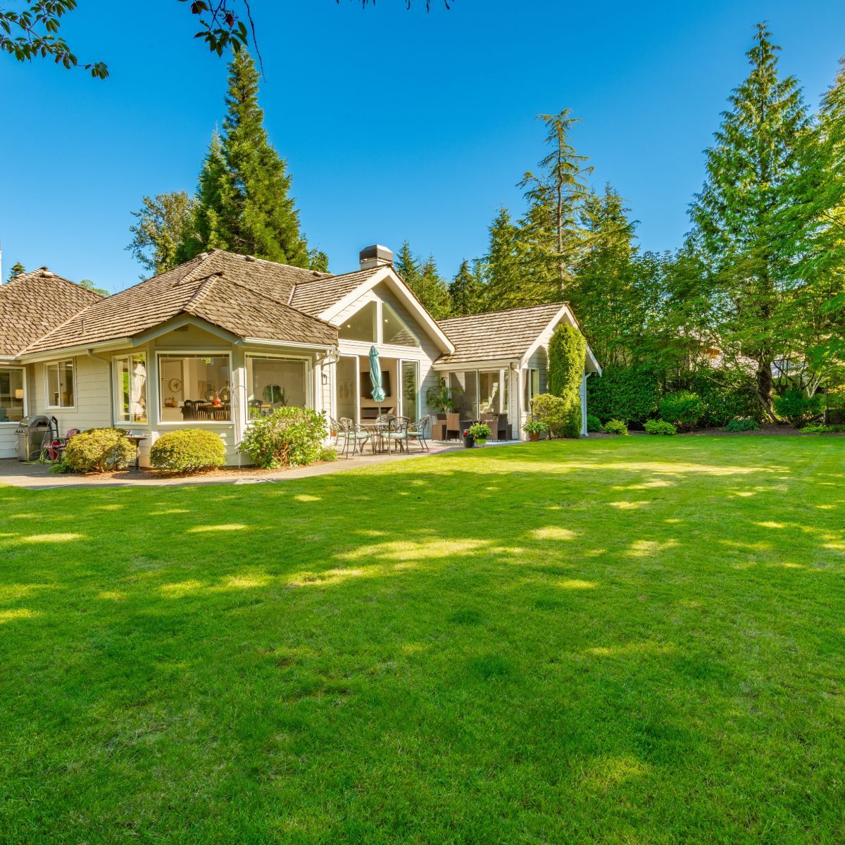 A white house with a large lush green lawn in front of it.