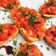 Tomato bruschetta on toasted bread, topped with herbs and balsamic drizzle
