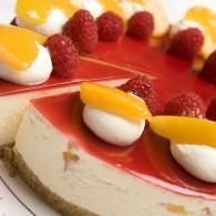 Red-and-white cake topped with raspberries and peach slices on a white plate