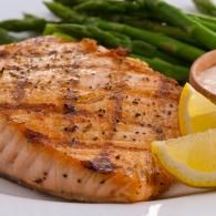Grilled salmon fillet with asparagus and lemon wedges on a white plate