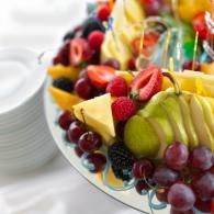 Colorful fruit platter with strawberries, grapes, kiwi, and pineapple on a white table
